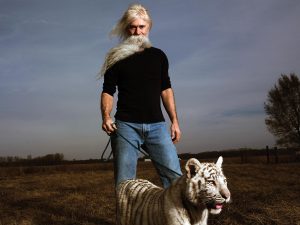 Tiger breeder with white tiger cub on leash from the documentary film "The Tiger Next Door"
